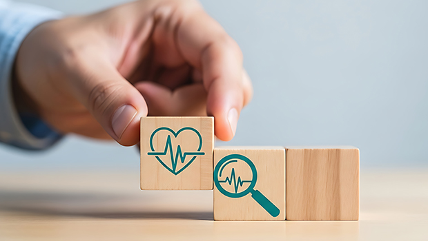 Eine Person legt Holzw&uuml;rfel nebeneinander, bei der sich ein Herz und eine Lupe miteinander verbinden.