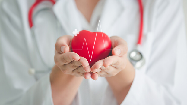 Eine &Auml;rztin h&auml;lt ein rotes Herz, &uuml;ber dem ein plus erscheint.